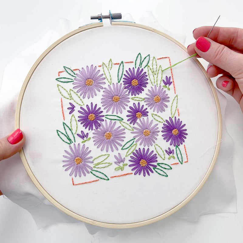 hands holding and stitching on the Asters embroidery kit from Penguin & Fish